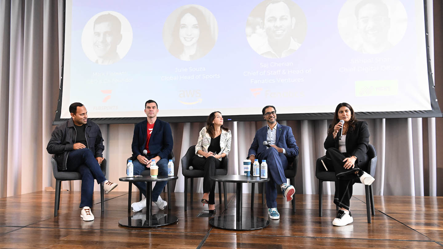 group of speakers sitting on stage, with one addressing the audience